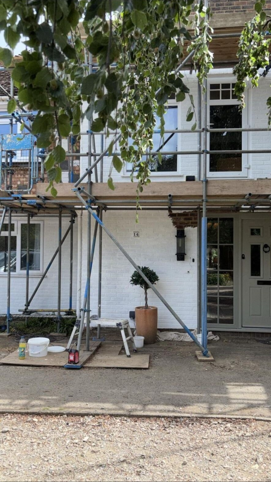 Scaffolded white-brick house elevation prepared for exterior painting